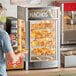 A man putting chips into a ServIt countertop display warmer.