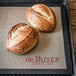 Two loaves of bread on a de Buyer perforated silicone baking mat.