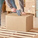 A person using a tape gun to seal a Lavex shipping box.