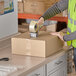 A person using a tape gun to seal a Lavex shipping box.