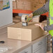 A man in a safety vest using a tape gun to seal a Lavex cardboard shipping box.