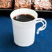 A white WNA Comet Classicware plastic coffee cup filled with brown liquid on a blue surface.