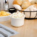 A Tuxton eggshell embossed rim bouillon cup filled with macaroni and cheese on a table with a bowl of coleslaw and corn.