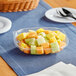 A Visions clear plastic bowl filled with cut fruit on a table.