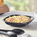 A Visions black plastic square bowl filled with coleslaw on a table.