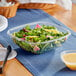 A Visions clear plastic square bowl filled with salad on a table.