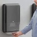 A man using a Tork Peakserve mini continuous paper towel dispenser.