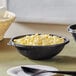 A Visions black plastic catering bowl filled with macaroni and cheese on a table.