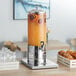 An Acopa stainless steel and polycarbonate beverage dispenser with orange juice.