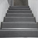 A close-up of a set of stairs with black Wooster Stairmaster treads.