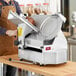 A man in an apron using a Estella heavy-duty meat slicer to cut meat.