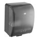 A black Tork mechanical paper towel dispenser with a clear plastic cover.