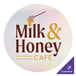 A white circle vinyl sticker with brown text reading "milk & honey cafe"