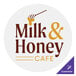 A white circle sticker with brown text and a stick with the text "milk & honey cafe" and the Carnival King logo.