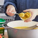 A person stirring Knorr Select Vegetable Base in a pot of food.