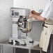 A man in a white apron mixing food in a Main Street Equipment Planetary Stand Mixer.