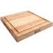 A John Boos maple wood cutting board with grooves on one side and handles on the other.