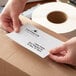 A person's hands holding a white Lavex Thermal Transfer label.