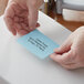 A person's hands holding a blue label from a Lavex Thermal Transfer Label roll.