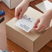 A person putting a white label on a cardboard box.