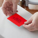 A person's hands holding a red Lavex thermal label.