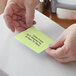 A person's hands holding a green Lavex thermal transfer label.