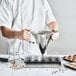 A person using a de Buyer stainless steel piston funnel to pour chocolate into a cupcake.