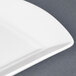 A close-up of a CAC Paris French bone white china fashion platter with a curved edge.