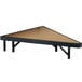 A National Public Seating pie-shaped stage unit with a brown hardboard surface and black legs.