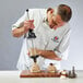 A chef using a de Buyer Le Tube pastry press on a wooden table.