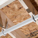 A white pipe attached to a wood ceiling with an Oatey DWV J-Hook.