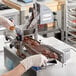 A person in gloves using a ChocoVision Revolation Delta chocolate tempering machine to make chocolate.