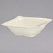 A white square bowl with a handle on a white surface.