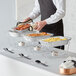A man using Choice disposable chafing dishes to serve food on a table.