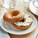 A Schar gluten-free cinnamon raisin bagel with cream cheese on a plate.