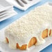 A cake with white frosting and shredded coconut on top.