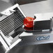 An Edlund tomato slicer slicing a tomato.