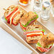 A white plate with sandwiches made with Schar Gluten-Free Multigrain Ciabatta Rolls, meat, and vegetables.