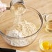 A person pouring Bob's Red Mill Organic Whole Grain Corn Flour into a bowl.