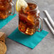 A glass mug with a Choice teal beverage napkin and a lemon slice on the rim.