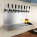 A row of beer taps on a Regency stainless steel wall mount beer drip tray.