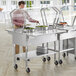 A man standing behind a stainless steel ice-cooled food table with a glass sneeze guard.