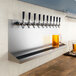 A row of beer taps on a wall with a Regency stainless steel beer drip tray underneath.