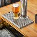 A glass of beer on a Regency stainless steel beer drip tray.