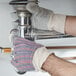 A person wearing Cordova leather work gloves with a palm patch fixing a pipe.