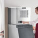 A man pressing a button on a Scotsman air cooled ice machine.