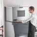 A man in an apron standing next to a Scotsman air cooled ice machine.