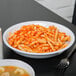 A Diamond White melamine deep bowl filled with pasta in sauce with a fork.