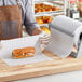 A man in an apron holding a roll of Choice wet wax paper on a bakery counter.