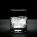 A glass with ice cubes sitting on a white surface.